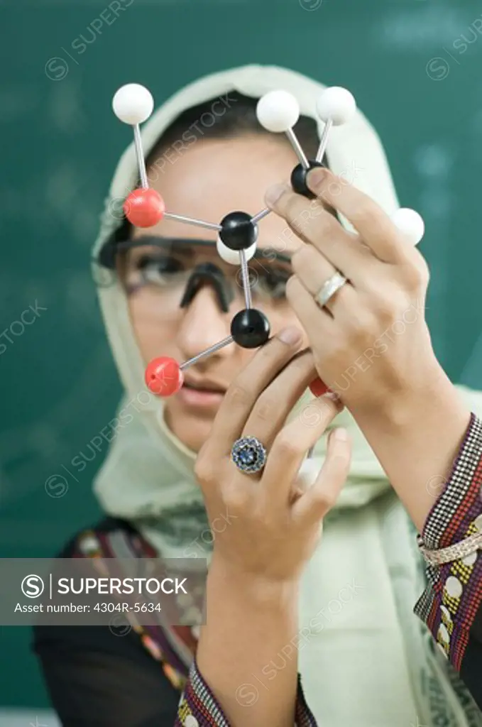 Young woman (20-25) holding DNA model, close-up