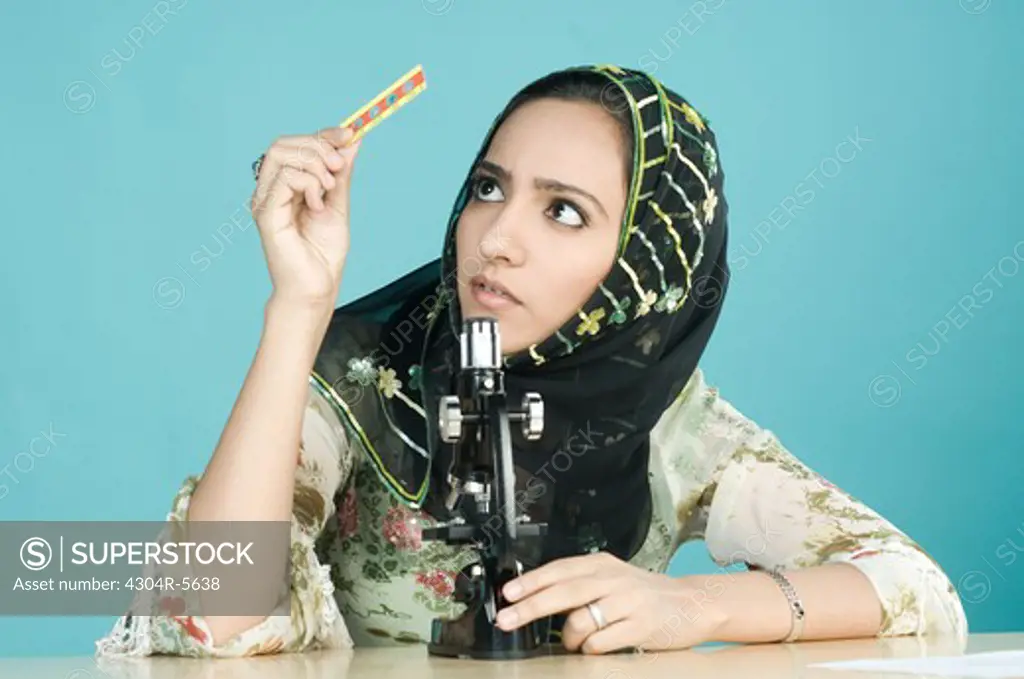 Woman with microscope looking at microscope slide