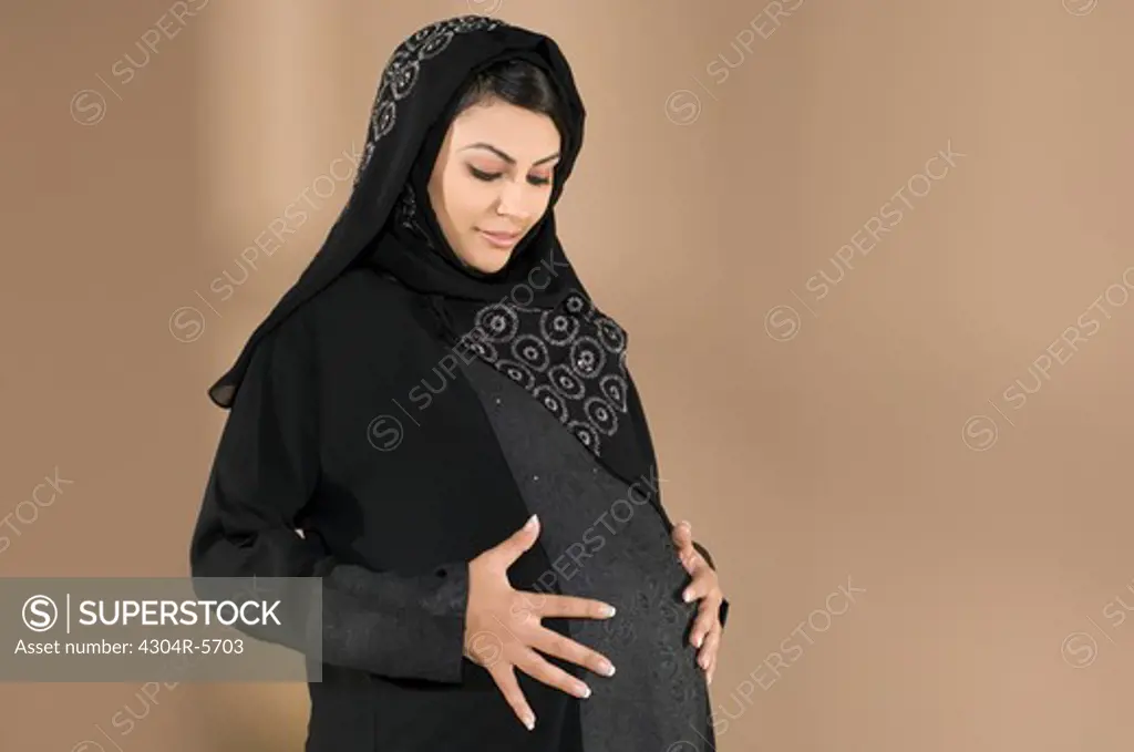 Pregnant woman touching abdomen, smiling
