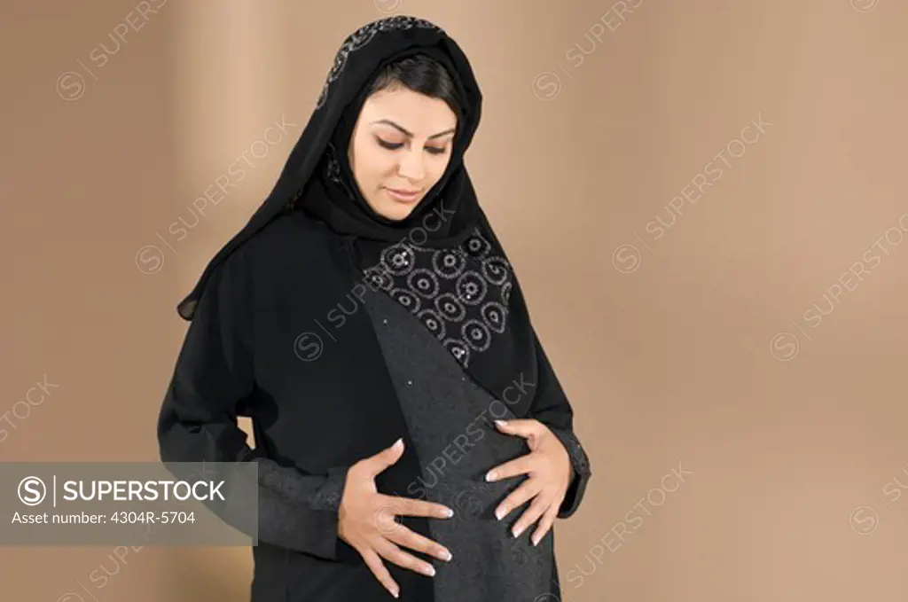 Pregnant woman touching abdomen, smiling