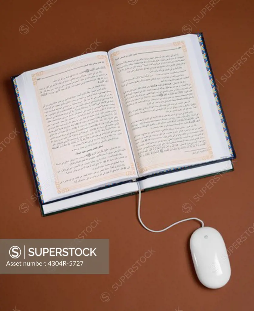 Computer mouse wire used as bookmark in book,close-up,elevated view