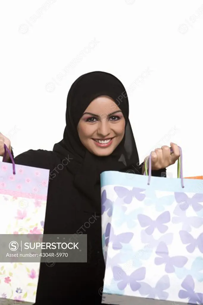 Young woman holding paper bags, smiling, portrait