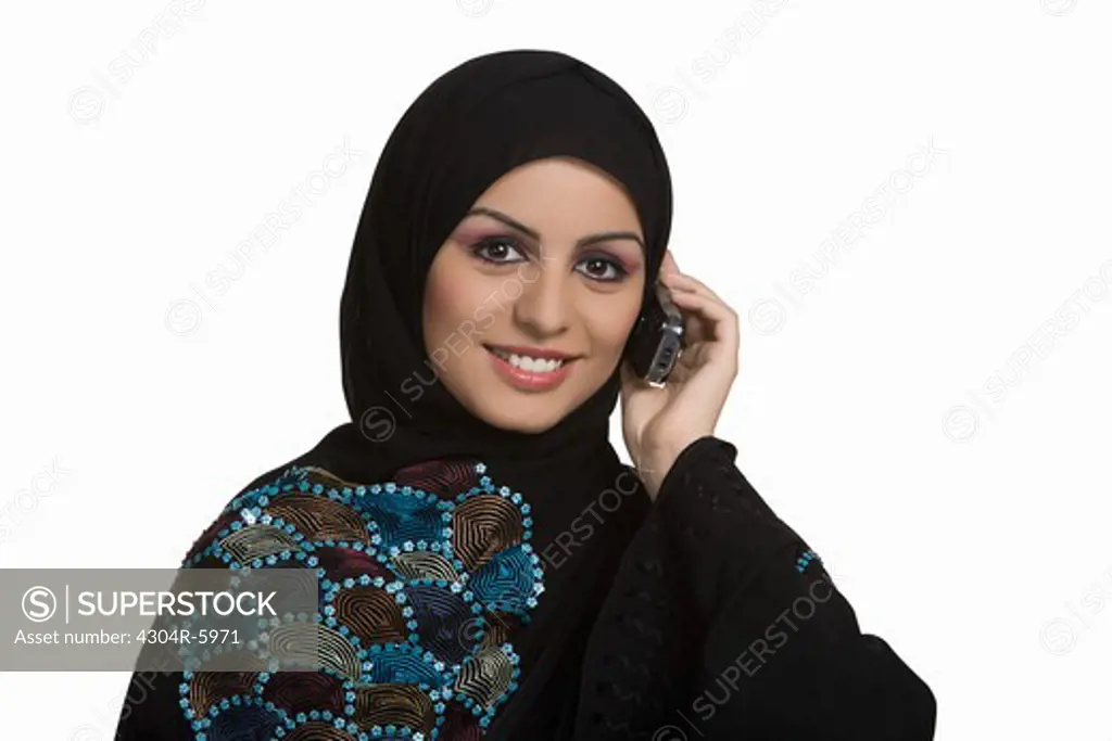 Young woman conversing on mobile phone, smiling, portrait