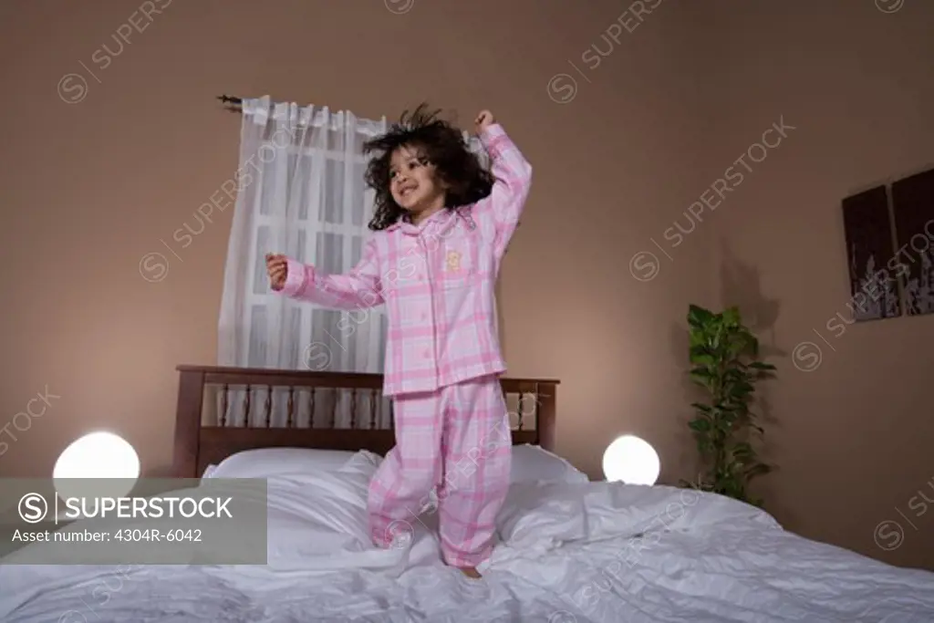 Girl (3-4) dancing on bed
