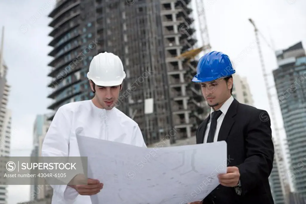 Businessmen looking at blueprint at construction site