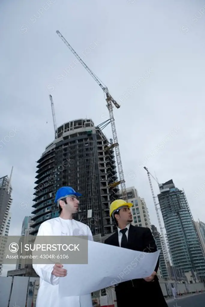 Businessmen holding blueprint at construction site