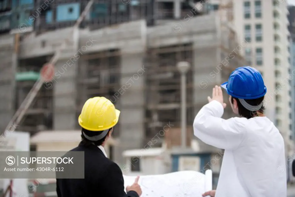 Businessmen discussing at construction site, rear view