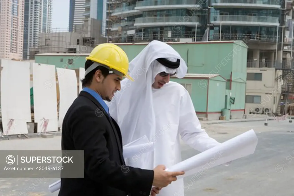 Businessmen looking at blueprints at construction site