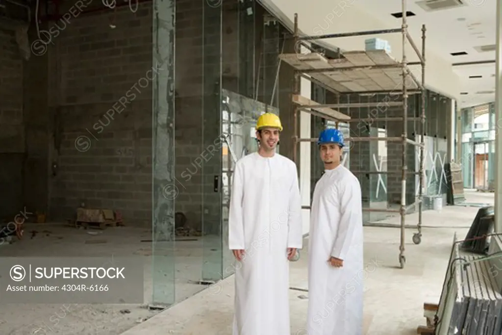 Businessmen at construction site, smiling, portrait