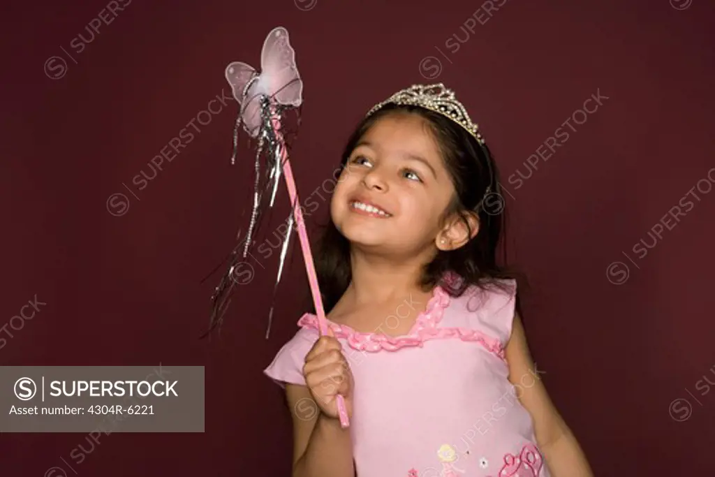 Girl holding magic wand, looking up