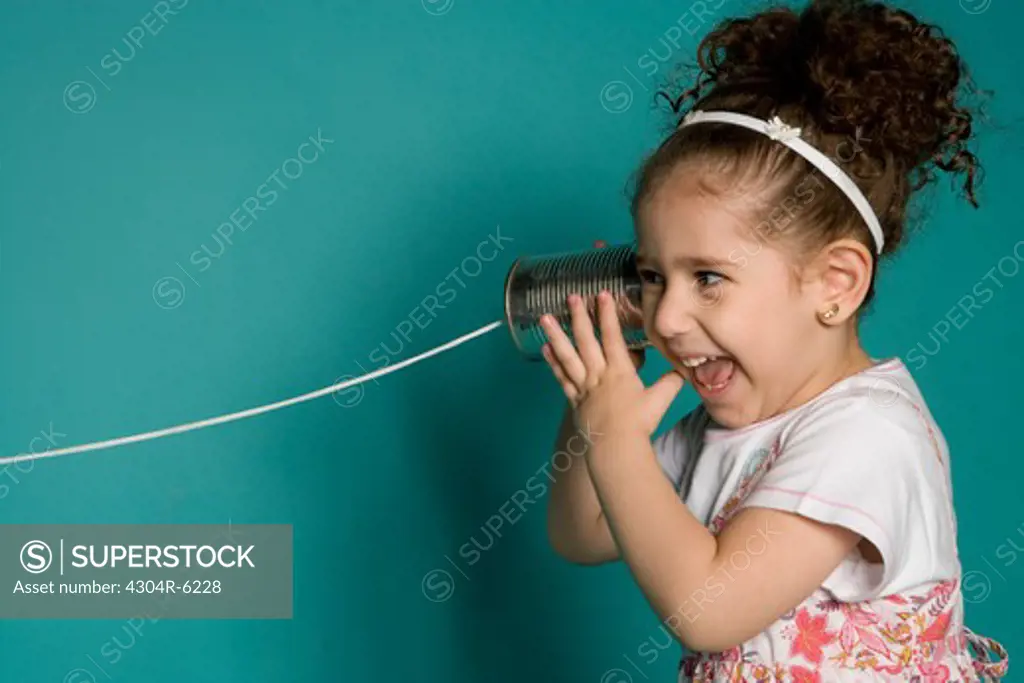 Girl holding tin can phone, smiling