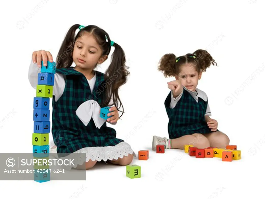 Girl playing with plastic blocks and friend in background