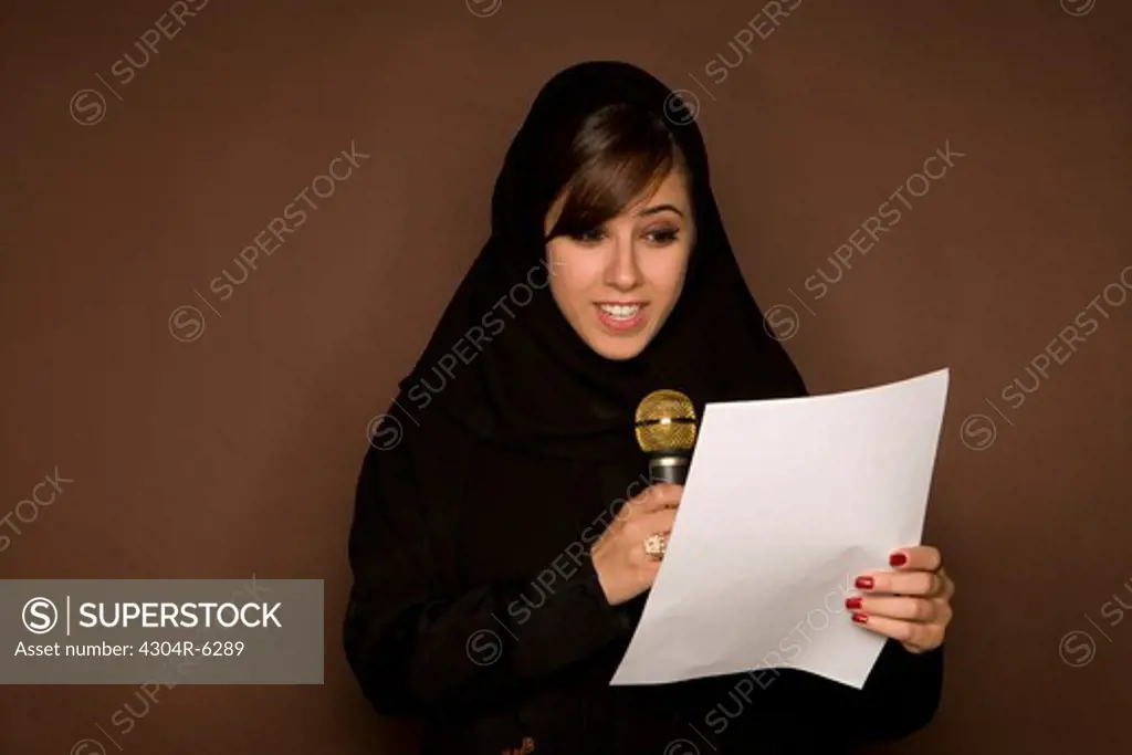 Young woman holding paper and microphone