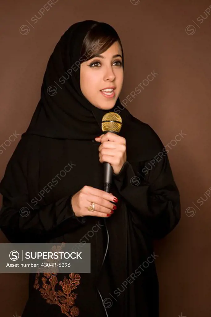 Young woman holding paper and microphone, portrait