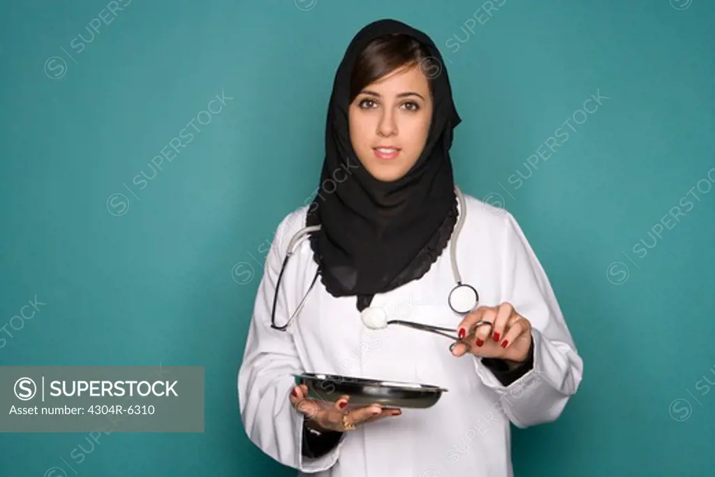 Female doctor holding medical tray and forceps, portrait
