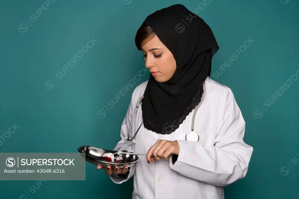 Female doctor holding medical tray and forceps