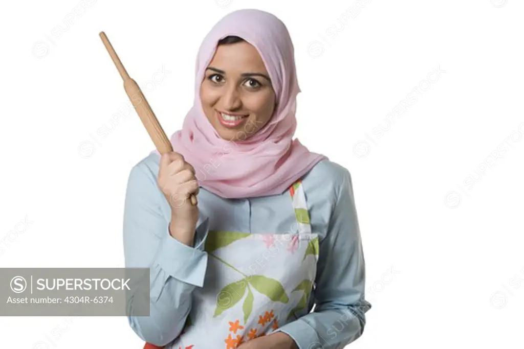 Young woman holding rolling pin, smiling, portrait