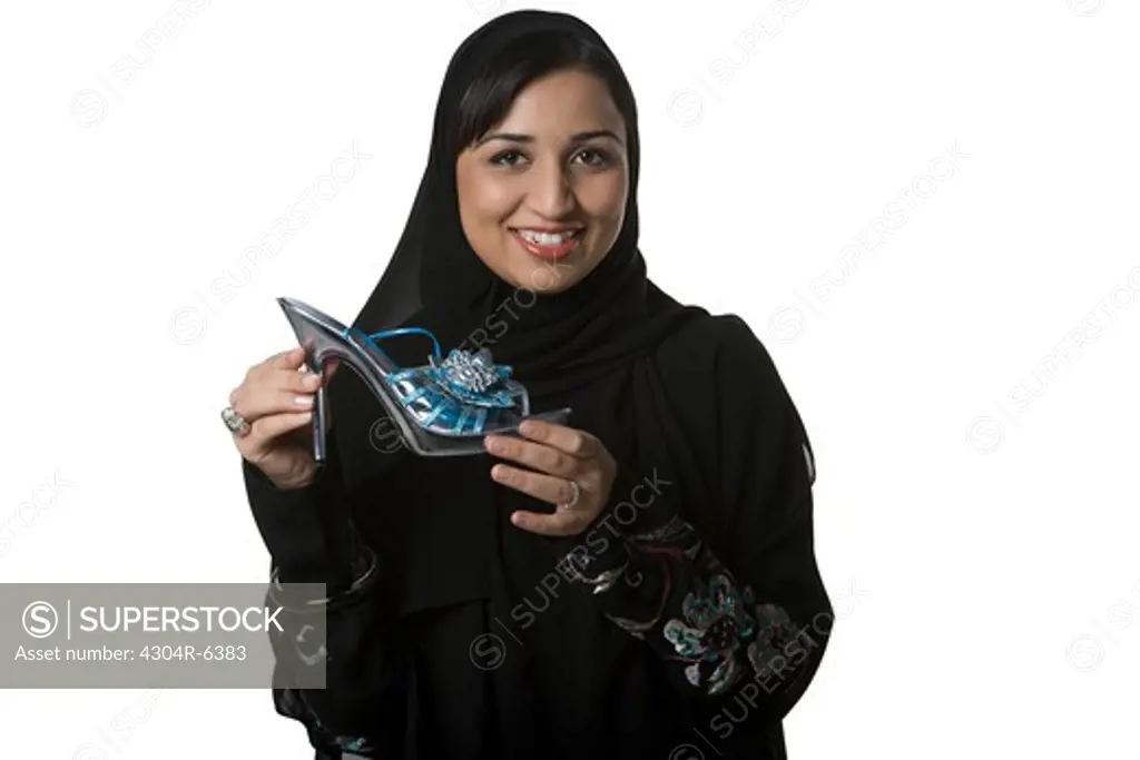 Young woman holding sandal, portrait