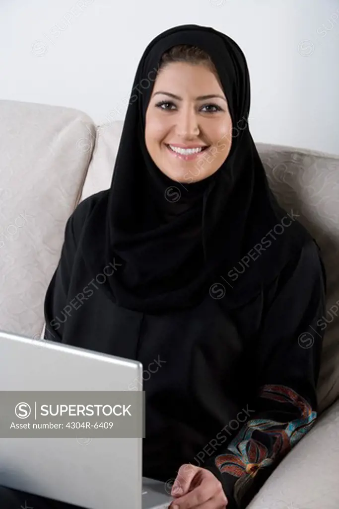 Young woman using laptop, smiling, portrait