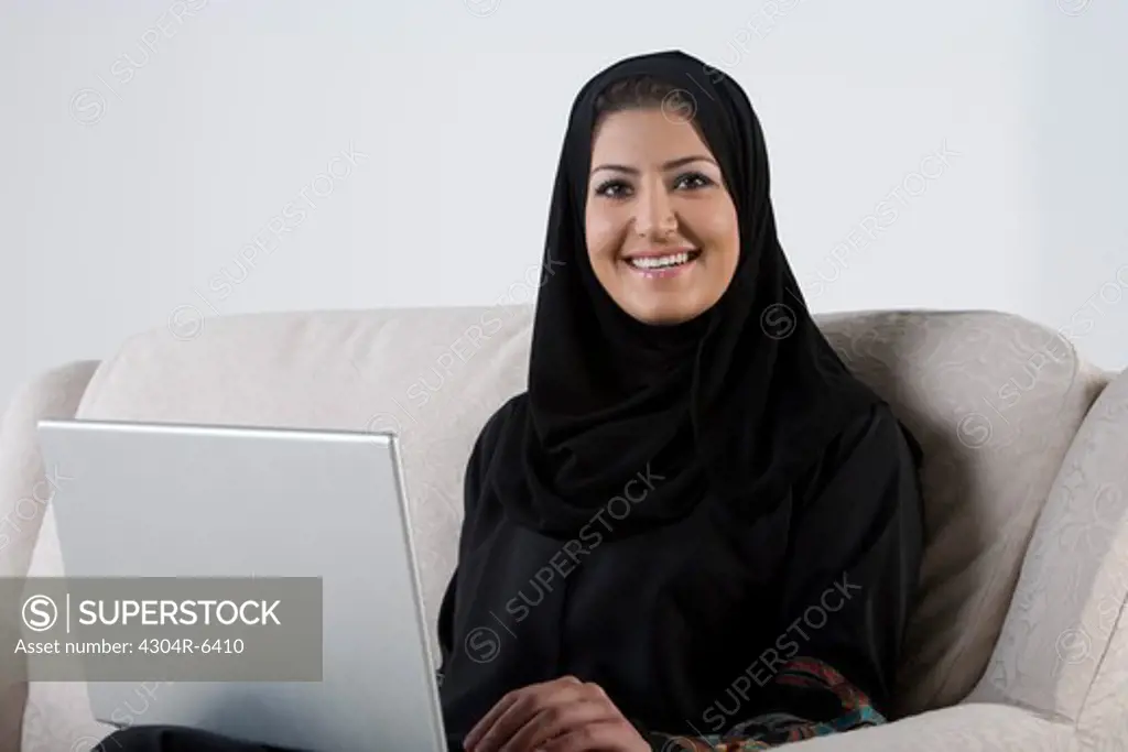 Young woman using laptop, smiling, portrait