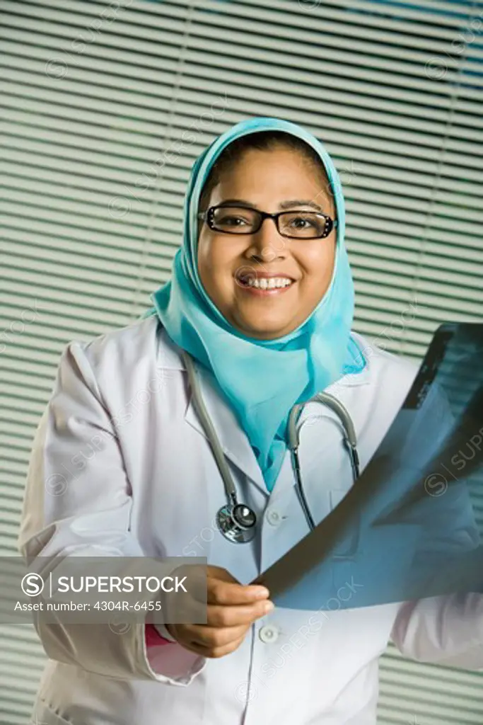 Female doctor holding X-ray, smiling, portrait