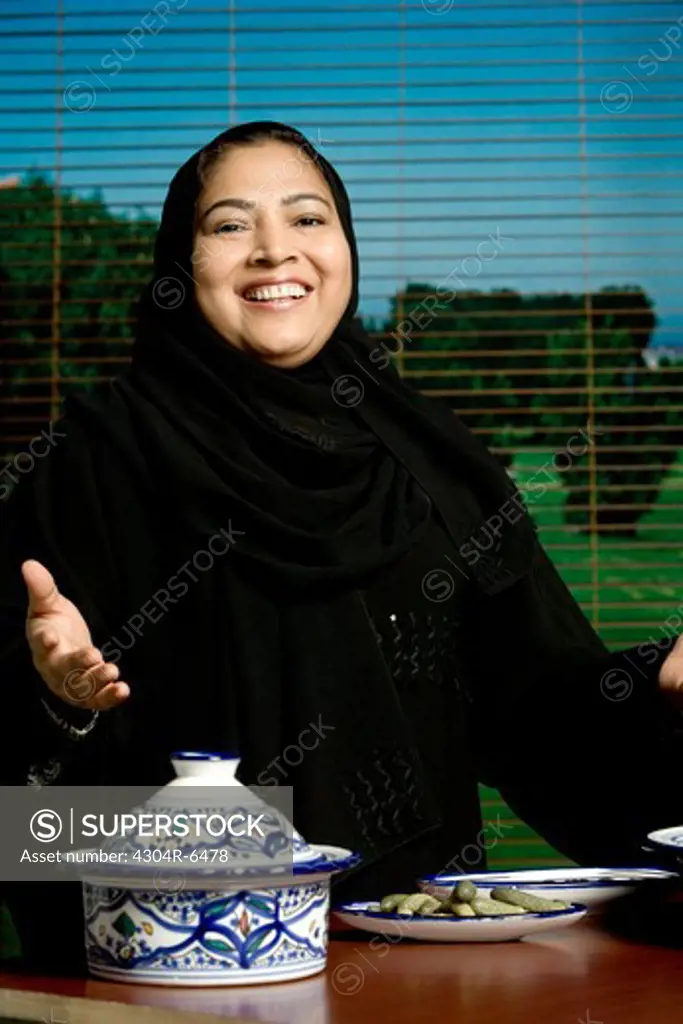 Woman gesturing with crockery in foreground, portrait
