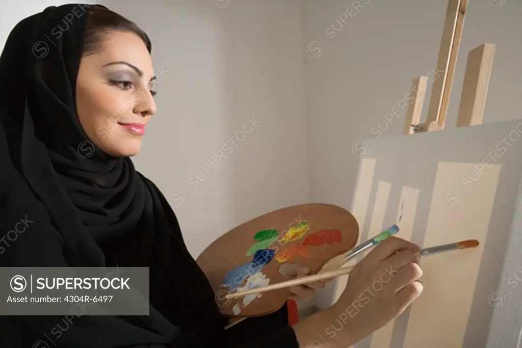 Young woman holding palette, painting, side view