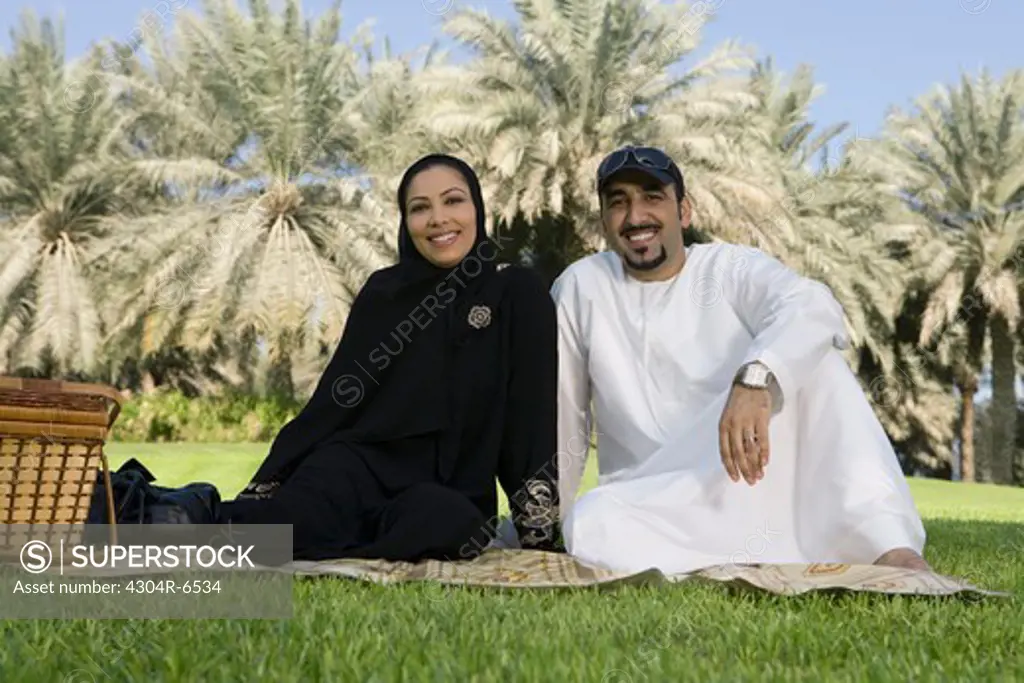 Mid adult couple sitting at park, smiling, portrait