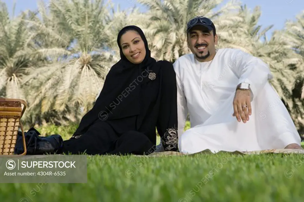 Mid adult couple sitting at park, smiling, portrait