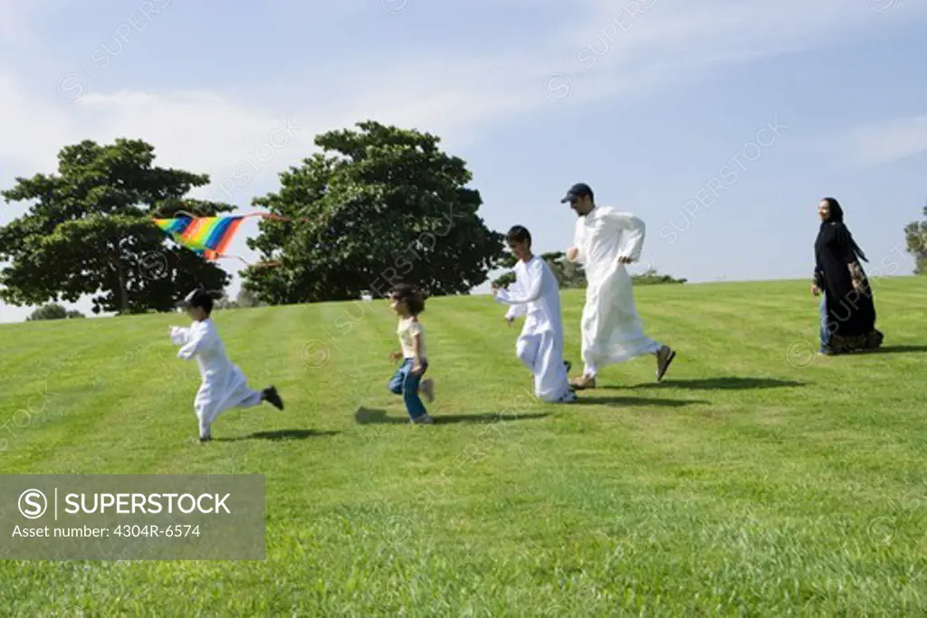 Father and children enjoying at park while woman standing in background