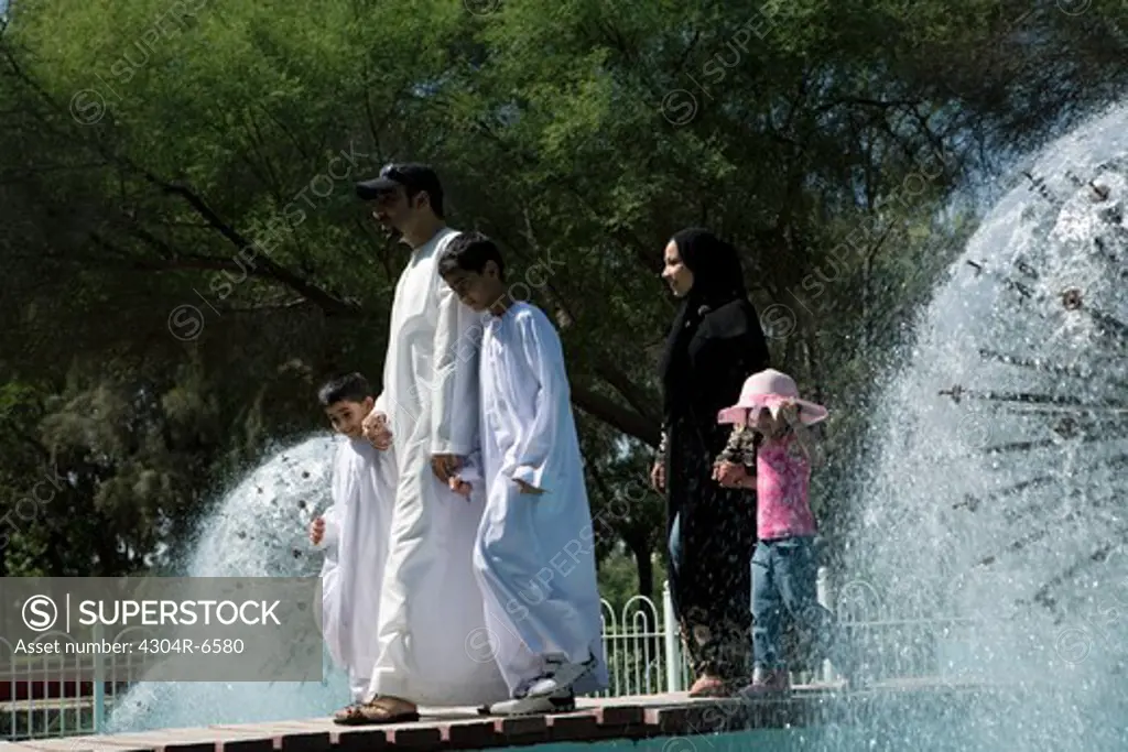 Parents with children walking by fountain
