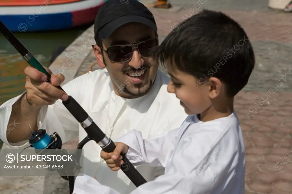 Father with son holding fishing rod, smiling, close-up