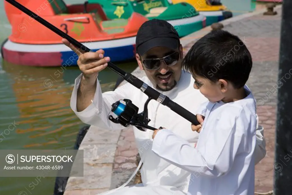 Father with son holding fishing rod, smiling,