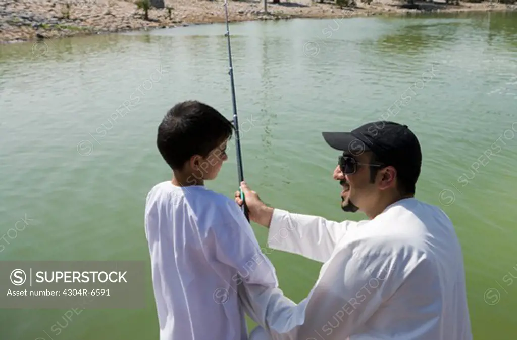 Father with son holding fishing rod, smiling