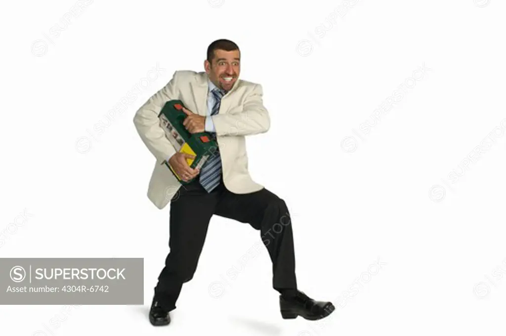 Mid adult man carrying car battery against white background