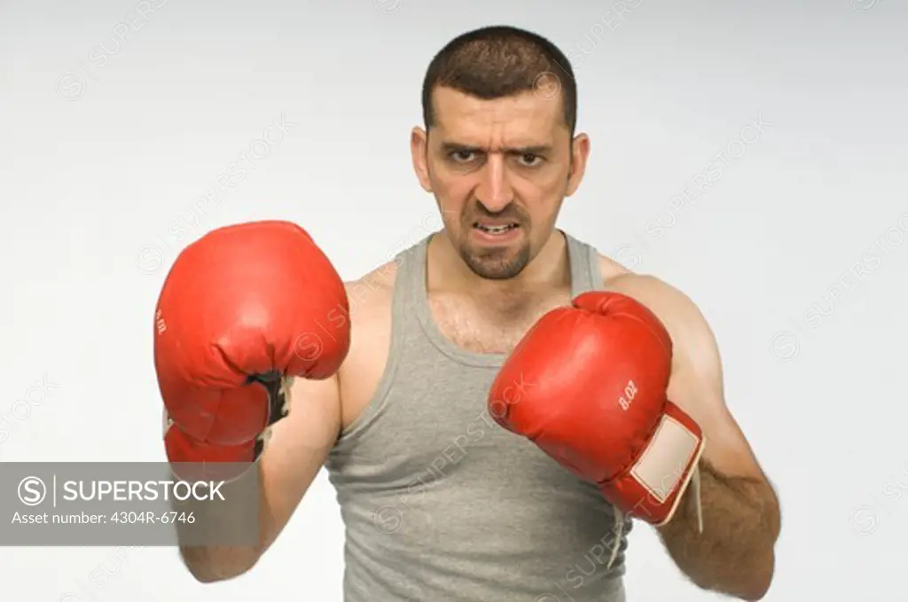Mid adult man with red boxing gloves standing against white background