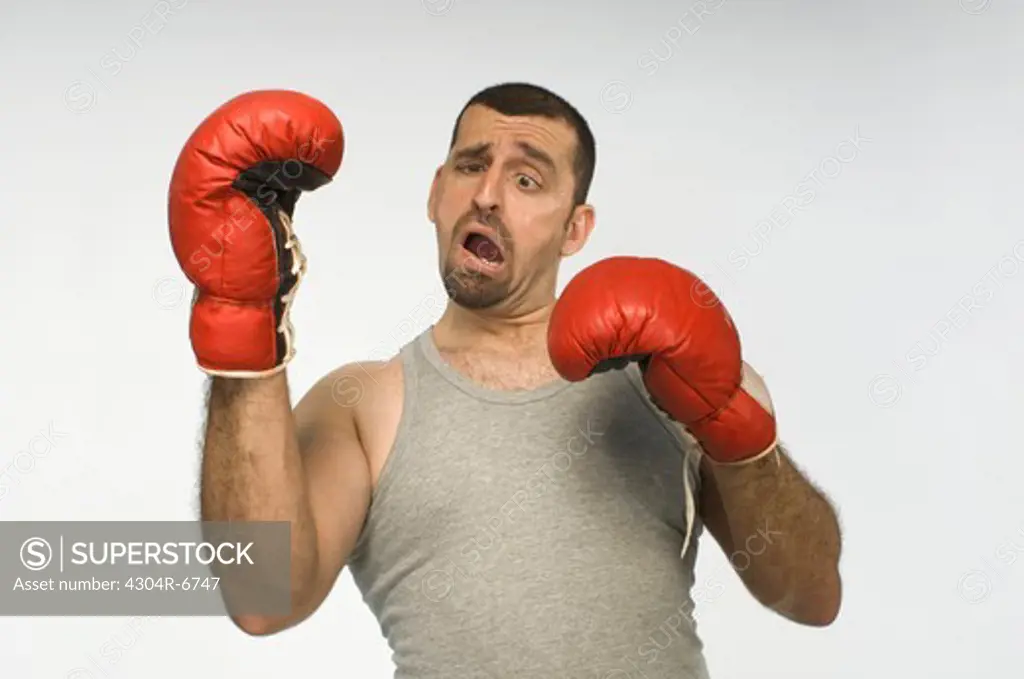 Mid adult man with red boxing gloves against white background