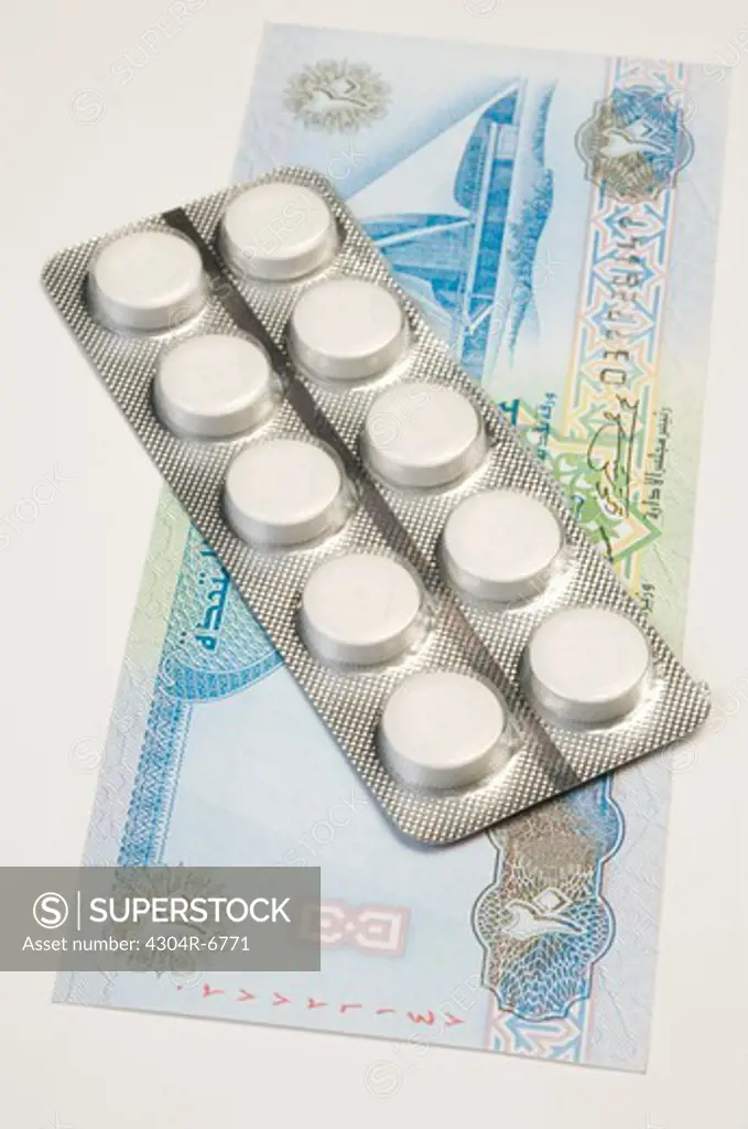 Blister pack with pills over currency notes, elevated view