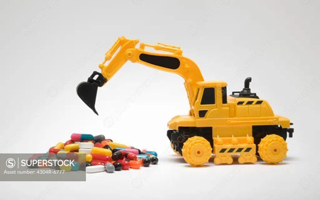 Toy crane lifting medicines against white background
