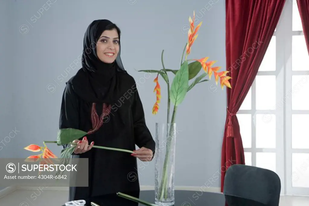 Arab woman arranging flowers in a vase