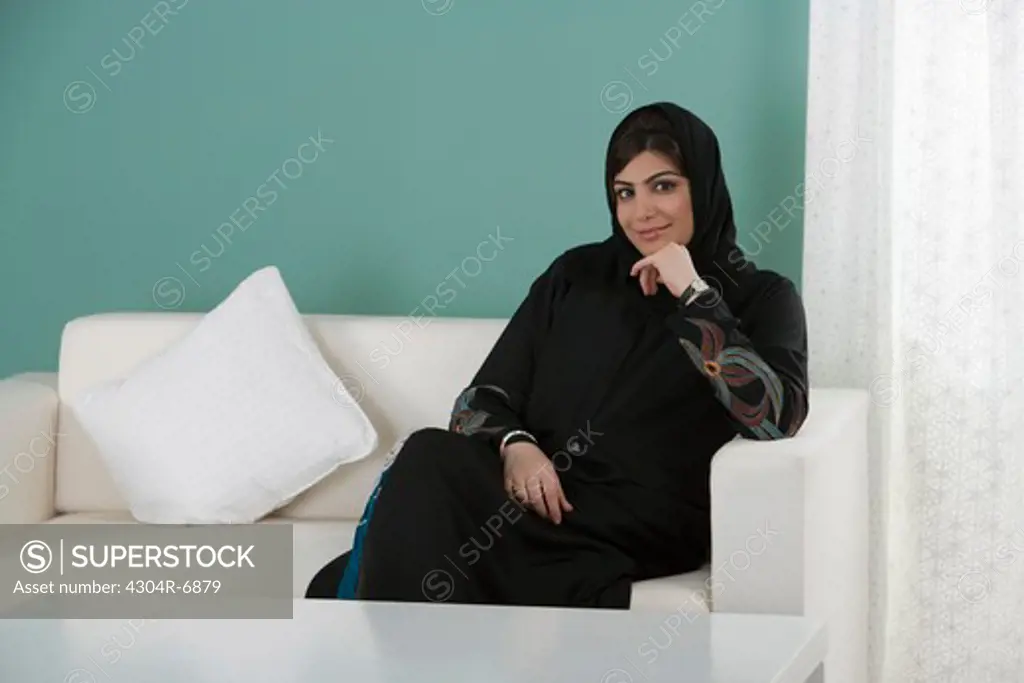 Arab woman sitting on sofa, smiling