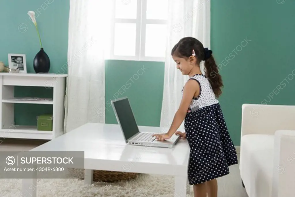 Girl (4-5 years old) using laptop at home