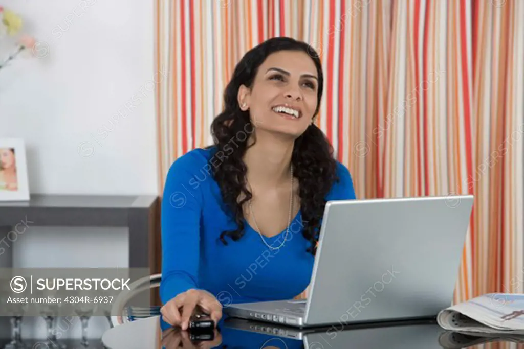 Woman holding her Cellphone at home, laughing
