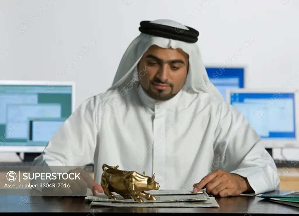 Arab man looking at the bull figurine on top of the table