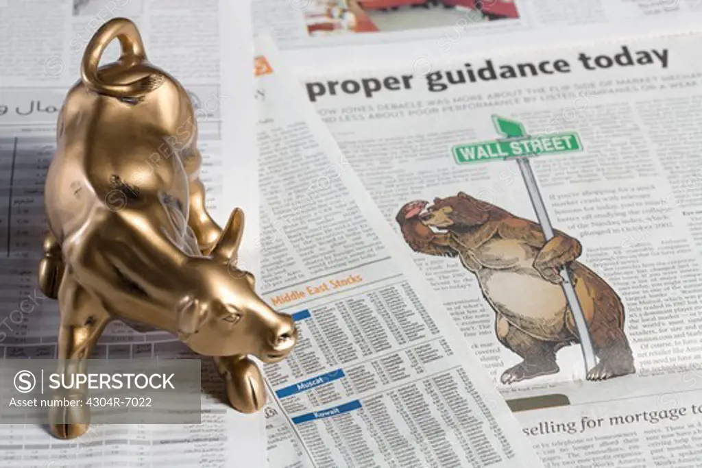 Bull figurine and bear on newspaper, close-up