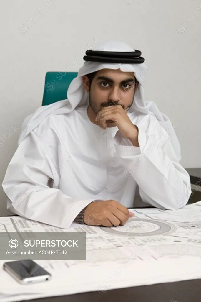 Arab businessman hands on chin, sitting at the office