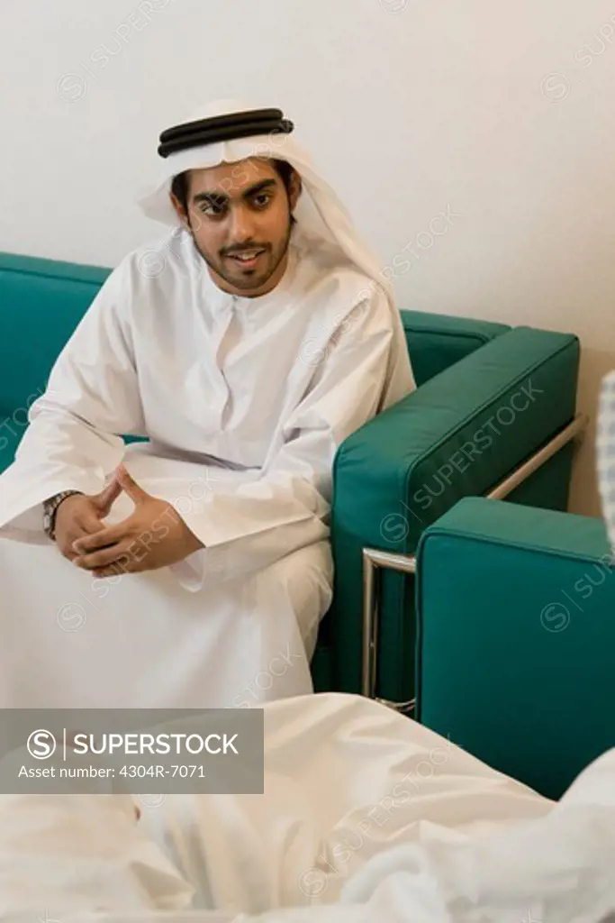 Two Arab businessmen sitting in office, discussing, smiling