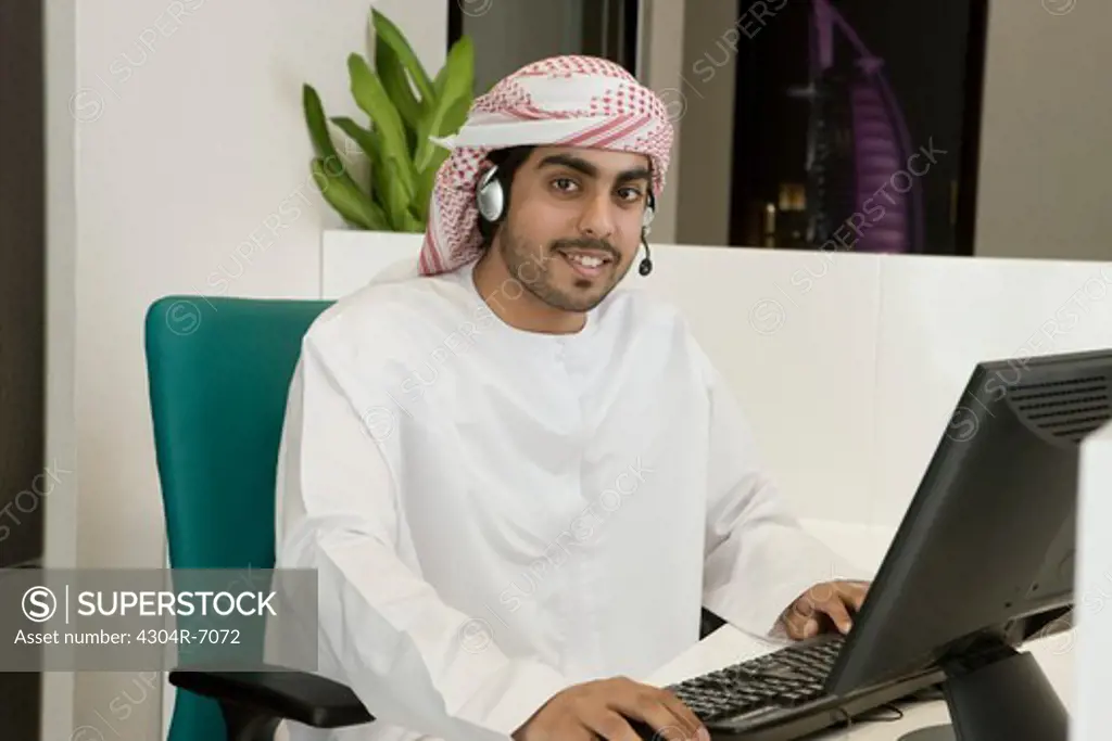 Arab man with headphones, sitting at the office