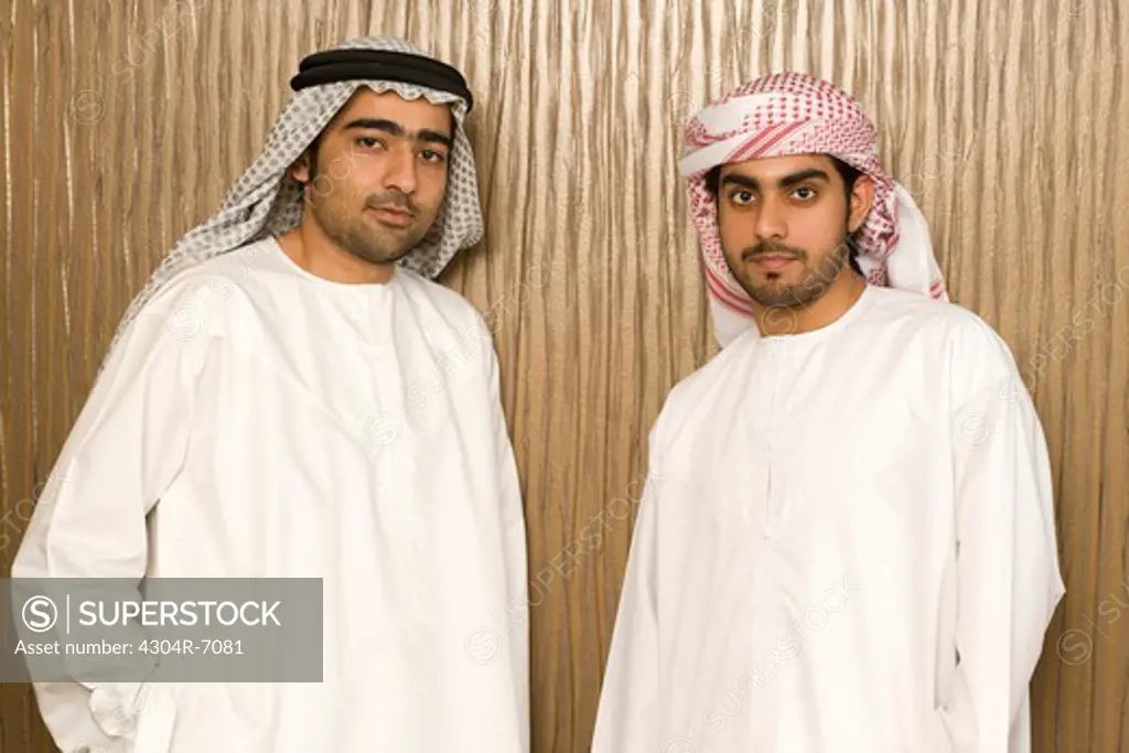Two Arab men standing near the office wall, portrait