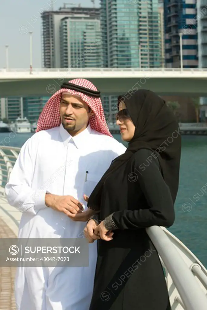 Arab couple standing by the railing in Dubai Marina, UAE